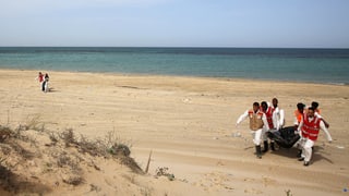 Mitarbeiter vom Roten Kreuz bergen eine Leiche an der libyschen Mittelmeerküste.