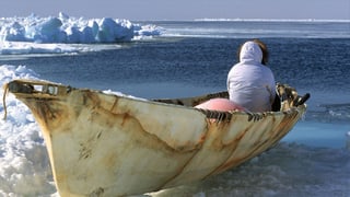 Ein Walfänger sitzt in seinem Boot und schaut aufs Wasser. 