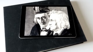 Zeichnung der Brüder Grimm auf einem Tablet, das aud einem dicken Buch liegt.