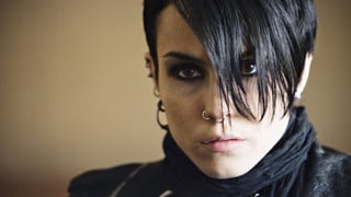 Eine Frau mit eher kurzen schwarz gefärbten Haaren und meheren Piercings im Gesicht.