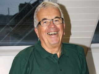 Markus Vogt mit grauen Haaren und Brille trägt ein dunkelgrünes Poloshirt und strahl in die Kamera.