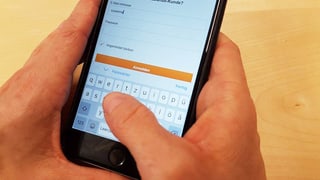 Hand tippt Login in ein Handy