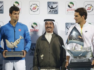 Novak Djokovic und Roger Federer posieren mit den Dubai-Trophäen, in ihrer Mitte ein Funktionär.