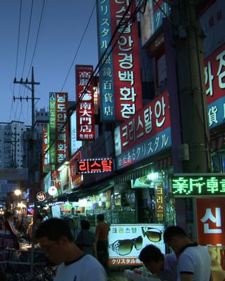 Impression einer beleuchteten südkoreanischen Einkaufsstrasse in der Abenddämmerung.
