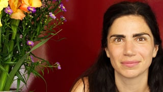 Dana Grigorcea sitzt neben einem Blumenstrauss.