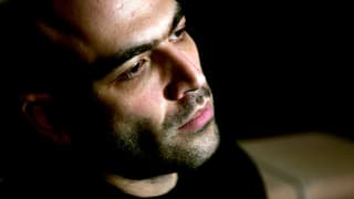 Porträtfoto von Robert Saviano, der im Halbdunkeln steht.
