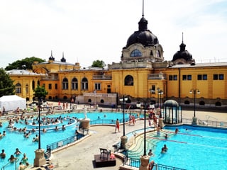 Die Aussenansicht eines neobarocken Bades mit hellblauen Swimmingpools.