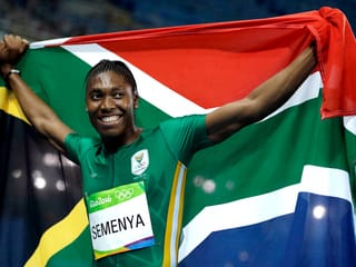 Caster Semenya hält lächelnd die südafrikanische Flagge über sich.