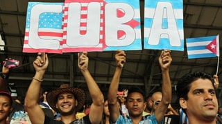 Zwei Männer mit Transparent. Darauf die US- und die kubanische Flagge und die Aufschrift «Cuba».