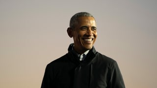Präsident Obama trägt einen schwarzen Mantel und grinst nach rechts. Präsident Obama trägt einen schwarzen Mantel und grinst nach rechts.