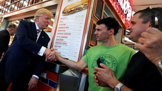 Donald Trump grüsst Menschen vor einem Restaurant.