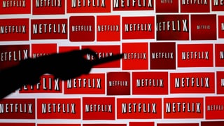 Eine Hand mit einer Fernbedienung vor Netflix-Logos