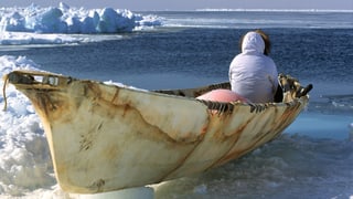 Inuit in einem Kanu, er schaut aufs Meer.