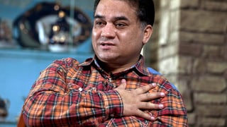 Ilham Tohti in kariertem Hemd. Die rechte Hand hat er auf seine Brust gelegt.