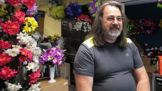 John Hensley sitzt lächelnd vor Blumen. John Hensley sitzt lächelnd vor Blumen.