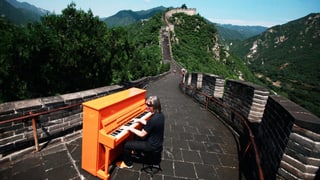 Ein Mann spielt Klavier auf der  Chinesischen Mauer.