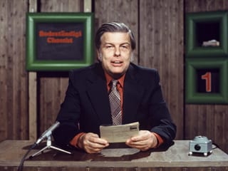 Ein Mann vor einem Mikrofon in einem Fernsehstudio.