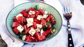 Ein Teller mit Stücke von Wassermelone und Fetakäse, zu einem Salat angerichtet.