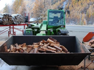 Transporter mit einerSchaufel voll Holzscheite.