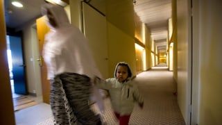 Verschleierte Frau mit Kind an der Hand geht durch Hotelflur