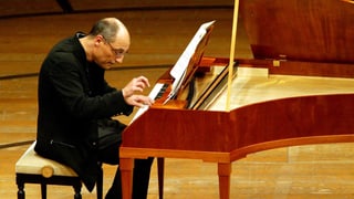 Mann sitzt gebeugt am Klavier.