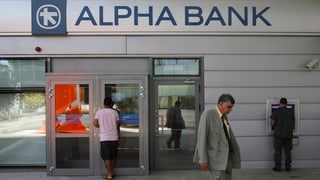Eine geschlossene griechische Bank, Menschen, die am Bankomat Geld abheben.