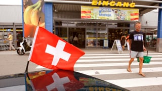 Eine Schweizer Flagge vor dem Eingang eines Deutschen Warenhauses