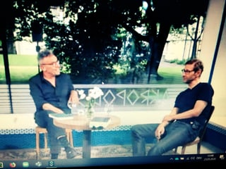 Ein Foto von Tom Kummer und Christoph Höhtker, die an einem Tisch sitzen und miteinander diskutieren.