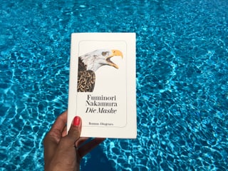 Annette König hält das Buch von Fuminori Nakamura: «Die Maske» vor blaues Wasser Annette König hält das Buch von Fuminori Nakamura: «Die Maske» vor blaues Wasser