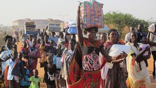 Eine Kolonne mit Südsudanesen, viele halten Gepäckstücke auf dem Kopf. Eine Kolonne mit Südsudanesen, viele halten Gepäckstücke auf dem Kopf.