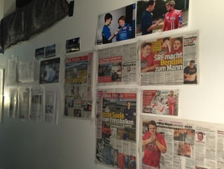 An einer Wand hängen Zeitungsartikel und Fotos