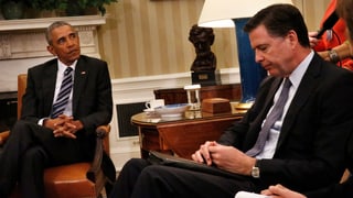 Barack Obama (links) sitzt schräg gegenüber von James Comey (rechts), der den Kopf gesenkt hat.