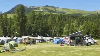 Viele Zelte, Wohnwagen und Wohnmobile auf einer Wiese.