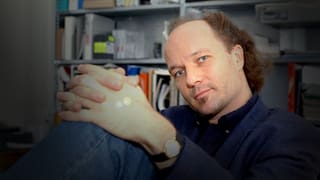 Regisseur Christian Frei sitzend vor einem Regal.