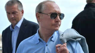 Putin mit Sonnenbrille in blauem Hemd.