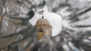Blick durch eine kaputte Fensterscheibe auf eine Kirche in Syrien.