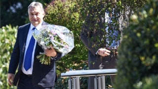 Viktor Orban hält einen Blumenstrauss.