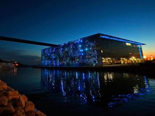 Museum bei Nacht, spiegelt sich im Meer