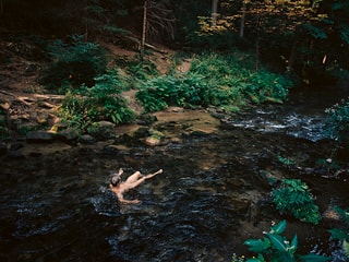 Ein nackter Mann badet in einem Fluss.