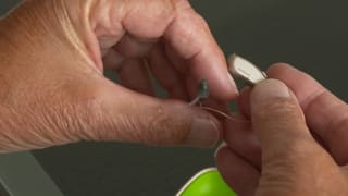 Mann mit Hörgerät in den Händen Mann mit Hörgerät in den Händen