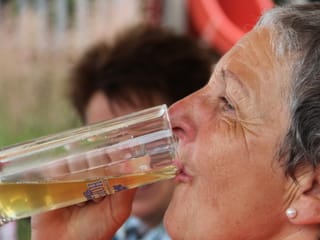 Eine Wanderin gönnt sich einen grossen erfrischenden Schluck Bier.