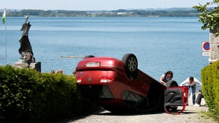 Ein Auto liegt auf dem Dach auf einer kleinen Strasse in Zug