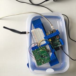 Ein Tupperware mit zwei Leiterplatten, einigen Kabeln und einer Antenne Ein Tupperware mit zwei Leiterplatten, einigen Kabeln und einer Antenne