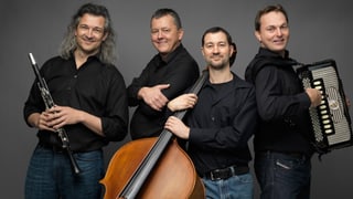Die vier Musiker in schwarzen Hemden und Jeans mit ihren Instrumenten.