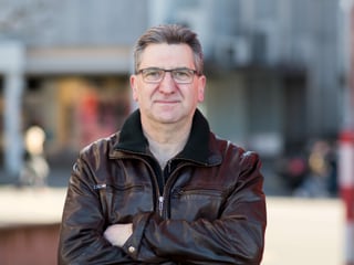 Ein Mann in Lederjacke mit verschränkten Armen. Ein Mann in Lederjacke mit verschränkten Armen.