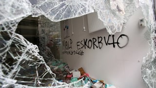 Blick durch eine eingeschlagene Fensterscheibe eines Geschäfts auf eine versprayte weisse Wand im Innern. Blick durch eine eingeschlagene Fensterscheibe eines Geschäfts auf eine versprayte weisse Wand im Innern.
