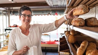 Verkäuferin greift nach einem Brot in Bäckerei. Verkäuferin greift nach einem Brot in Bäckerei.