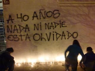 Graffiti an einer Wand: «Nach 40 Jahren: Nichts und niemand ist vergessen.». Am Boden scheinen Kerzen. 