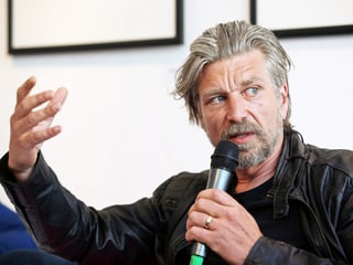 Karl Ove Knausgård hält ein Mikrofon. Er gestikuliert mit einer Hand. Karl Ove Knausgård hält ein Mikrofon. Er gestikuliert mit einer Hand.