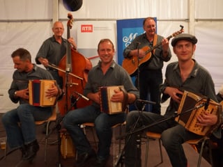 Fünf Musikanten mit ihren Instrumenten: drei Schwyzerörgeli, eine Gitarre und ein Kontrabass.